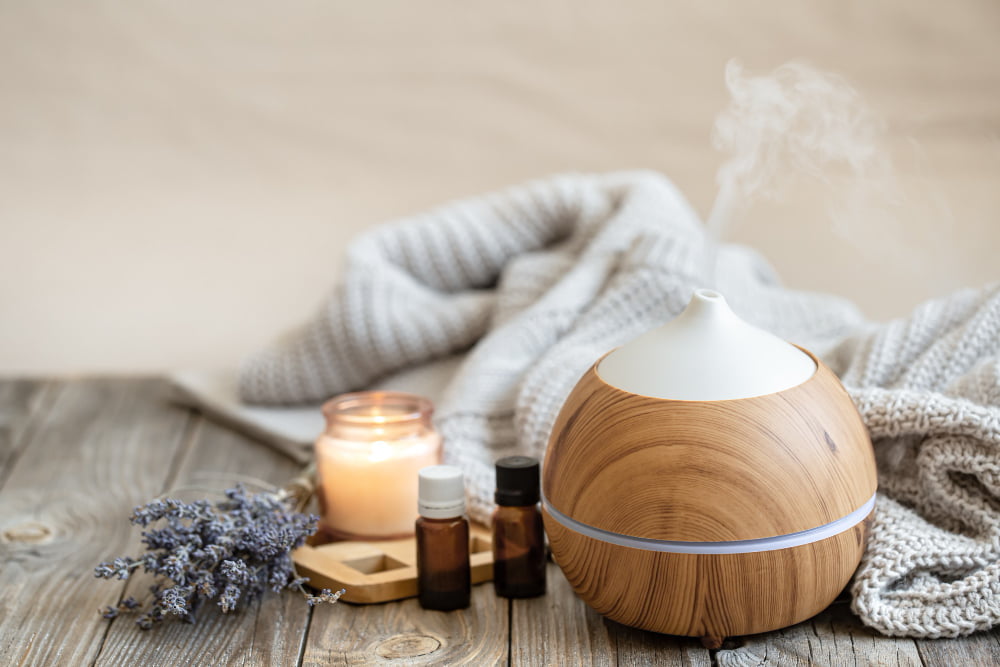 Benefícios da aromaterapia na vida: dicas e truques 4 modern aroma oil diffuser wood surface with knitted element candle lavender oil blurred background