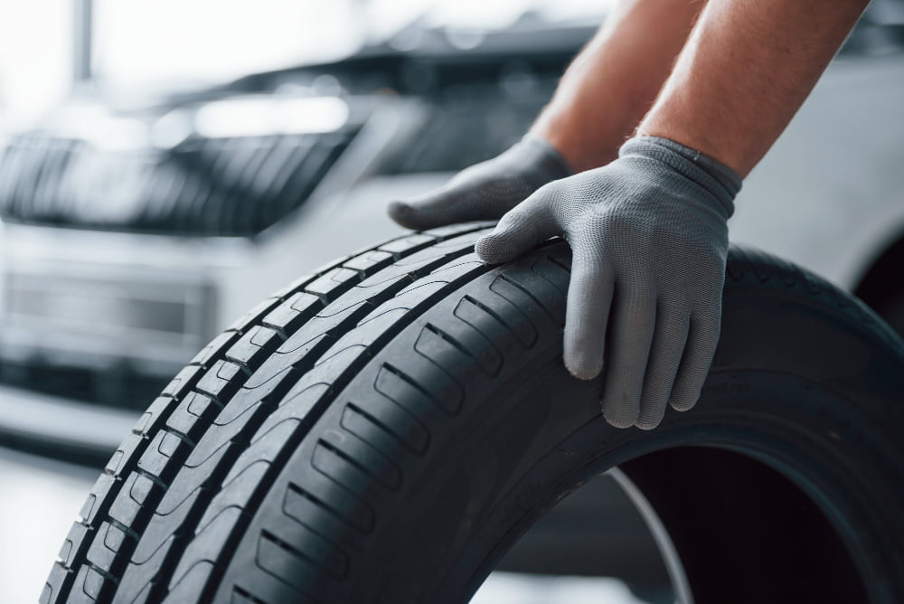 5 Dicas para prolongar a vida útil do veículo 3 hands only mechanic holding tire repair garage replacement winter summer tires