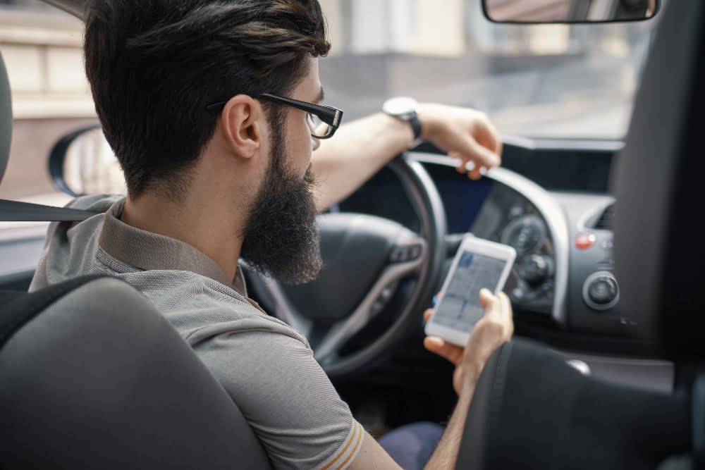 Como fazer o licenciamento digital sem sair de casa? 4 man using mobile phone while driving