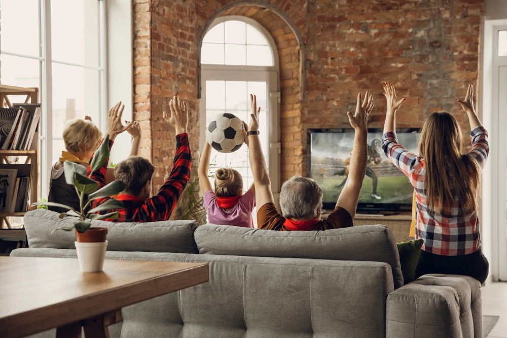 Como se divertir assistindo jogos: 10 dicas 3 excited happy big family team watch sport match together couch home