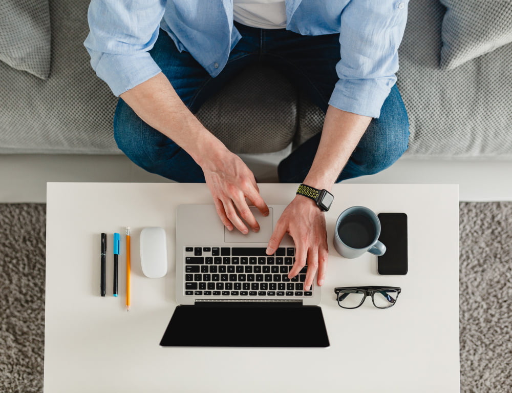 7 itens para renovar o home office e começar o ano com mais gás 2 table workplace close up man hands home working typing laptop