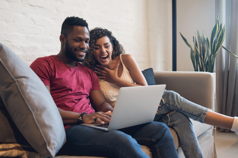Plano família de celular: será que vale a pena? 3 young couple spending time together while using laptop home new normal lifestyle concept