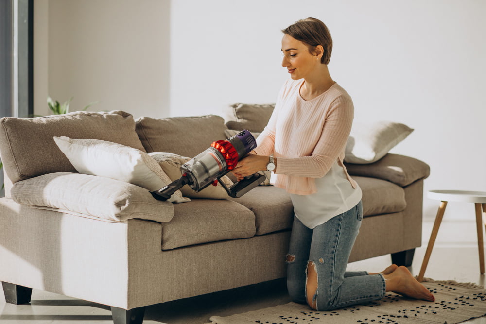 young woman with rechargeable vacuum cleaner cleaning home