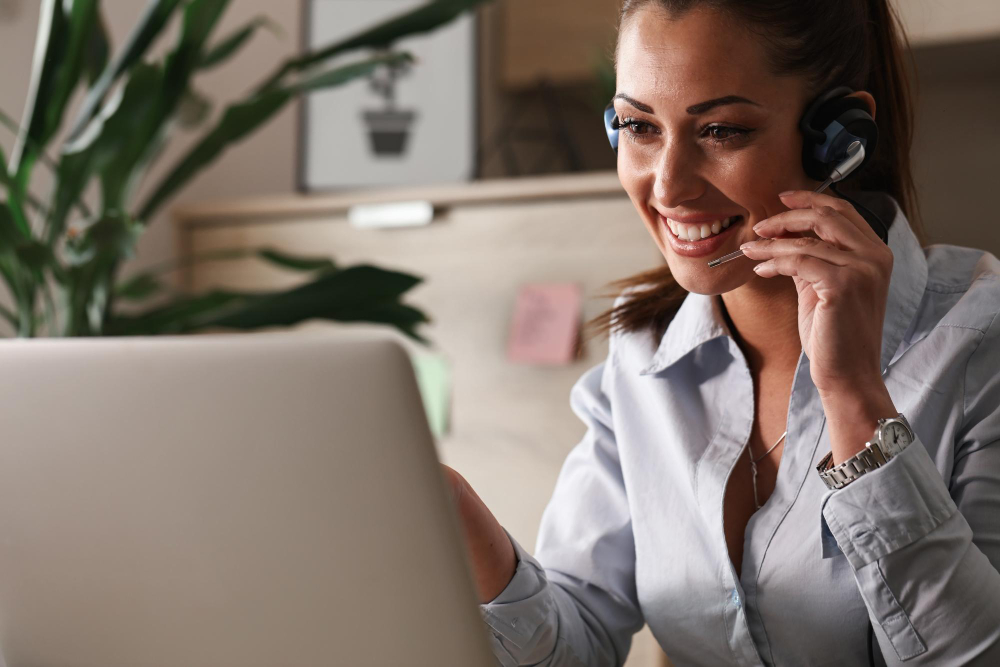 Como Economizar no escritório? Reduzir custos e recursos 3 feliz representante de atendimento ao cliente conversando com um cliente enquanto usa laptop no escritorio